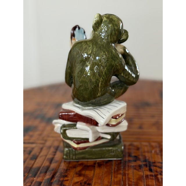 A wonderfully expressive ceramic monkey figurine holding a small mirror, full of the humor and personality that make...
