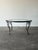 Sculpted blooms and curling vines wind down the four slender legs of this vintage Woodard coffee table, each ending in a...