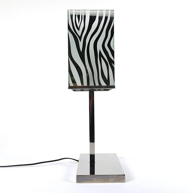 Stylish table lamp with a chrome base and mirror glass shade with zebra print. By the alternation of mirror glass and...