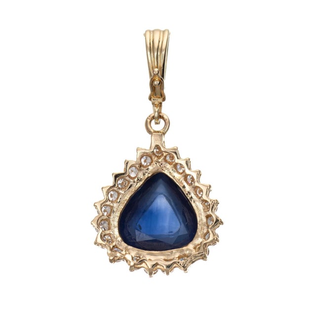 Finely detailed vintage natural Ceylon sapphire & diamond pendant crafted in 14 karat yellow gold. One pear shaped...