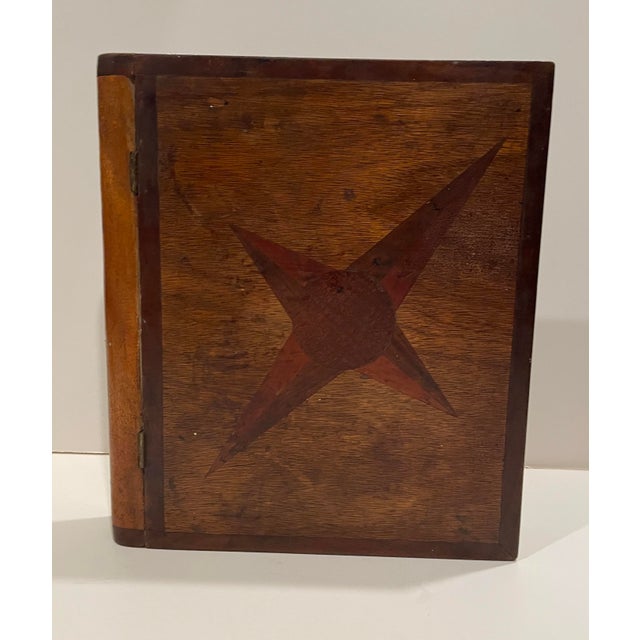 1930s antique folk art book form box with a hinged lid and parquetry compass on the cover. The edges are painted white and...