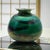 This hand-blown studio vase presents a rich iridescent green surface with subtle metallic shifting, achieved through...