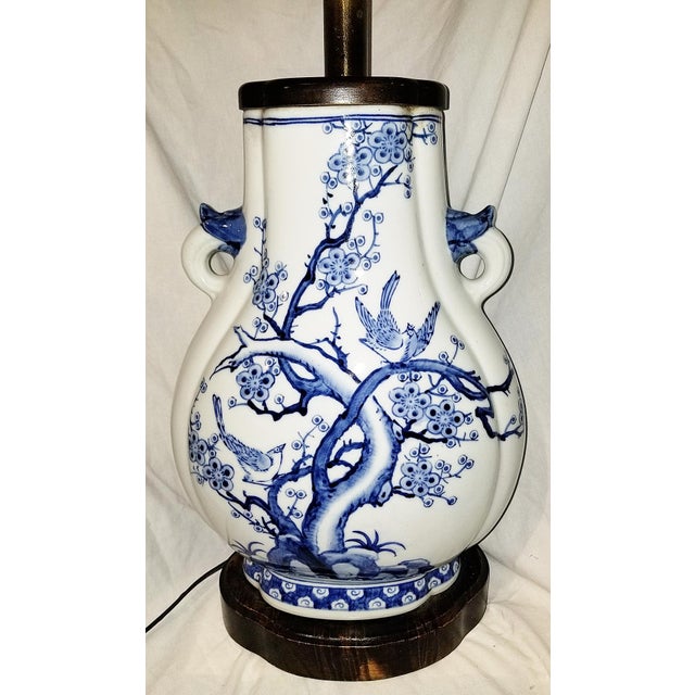 Modern day Chinese blue and white ceramic table lamp in bird and branch motif on wooden base. 15" H to socket