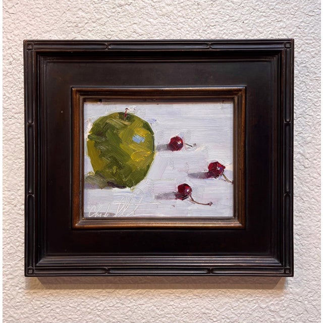 This oil painting features a vibrant green apple accompanied by several bright red cherries, set against a softly textured...