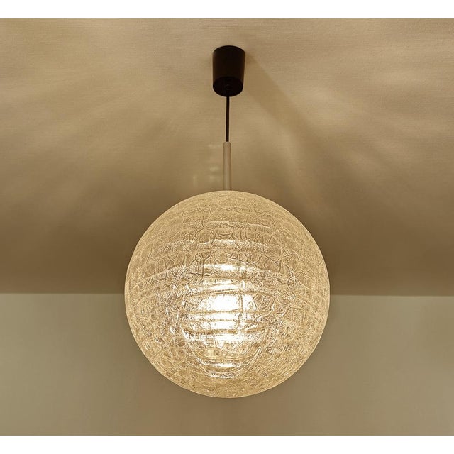 Very large mid century doria pendant light featuring a glass globe shade with a reliefed grid pattern, brass glass cap,...