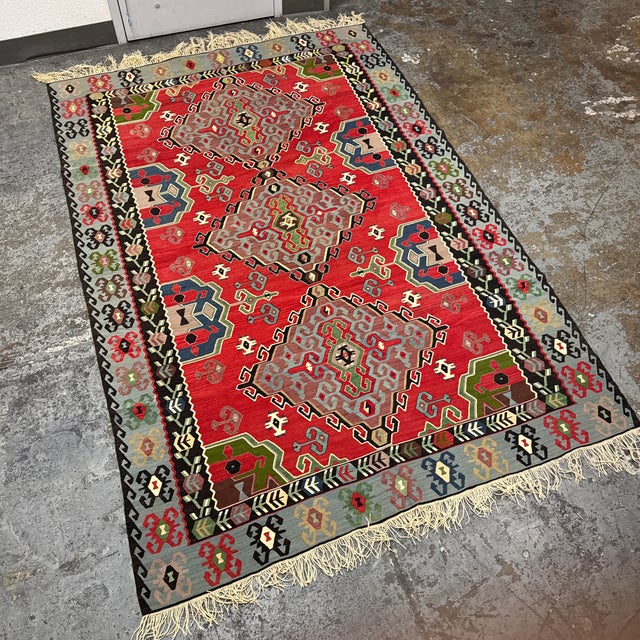 Design Plus Gallery presents a 6ft 4in × 10ft 6in Turkish Kilim Area Rug. This flatwoven rug has a red field with three...