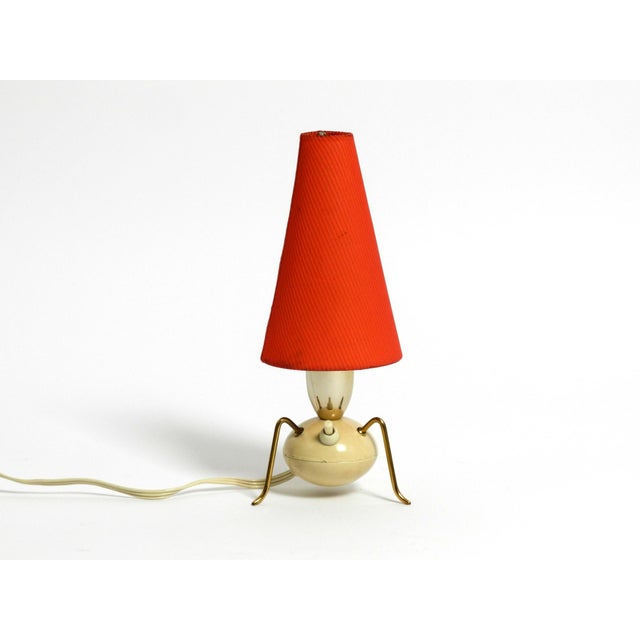 Beautiful rare original Mid Century Modern brass tripod table lamp with original red fabric lampshade. Typical 1950s high-...