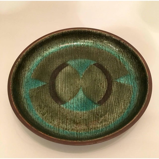 A 1960s handmade enamel over copper with an abstract design in colors of black, and olive and teal green. Signed. Located...