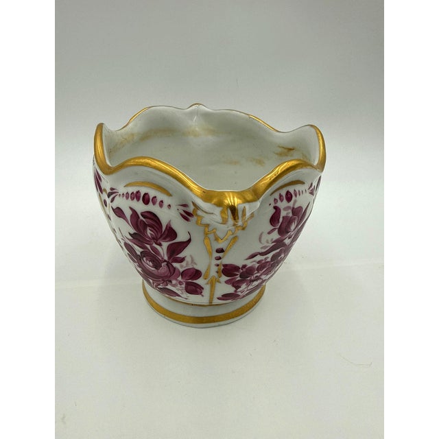 French porcelain cachepot / planter with a scalloped gilt rim and hand-painted magenta (puce) floral panels. Marked 'LM —...