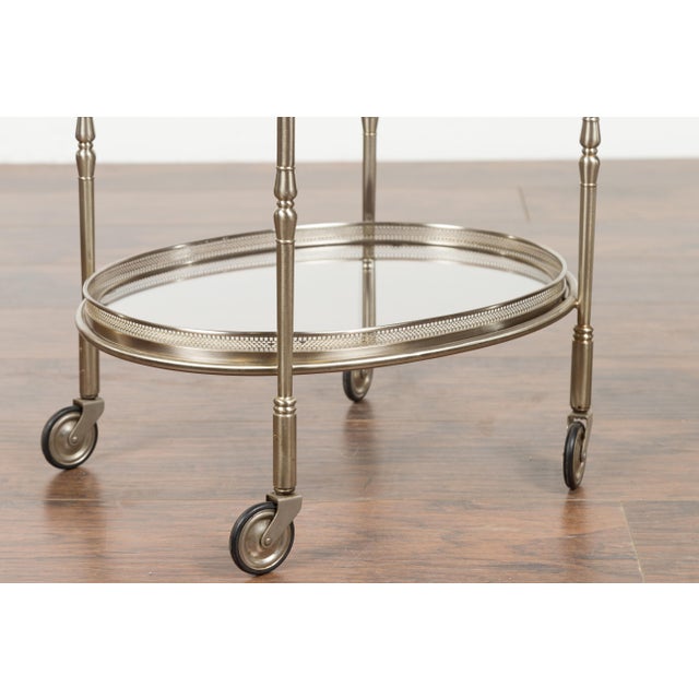 A vintage Italian oval steel trolley from the mid-20th century, with pierced gallery, mirrored shelves and casters....