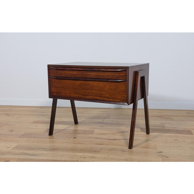 This Mid-Century rosewood console table was produced in Denmark in the 1960s.The console has profiled handles, giving it a...