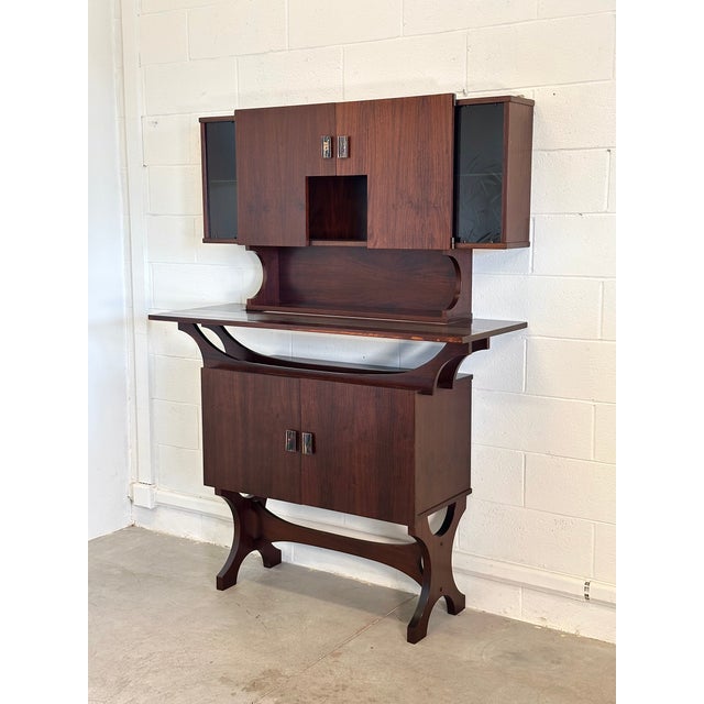 This 1960s-style mahogany bar cabinet consists of a sideboard and a wall cabinet with doors. The lower section can be set...