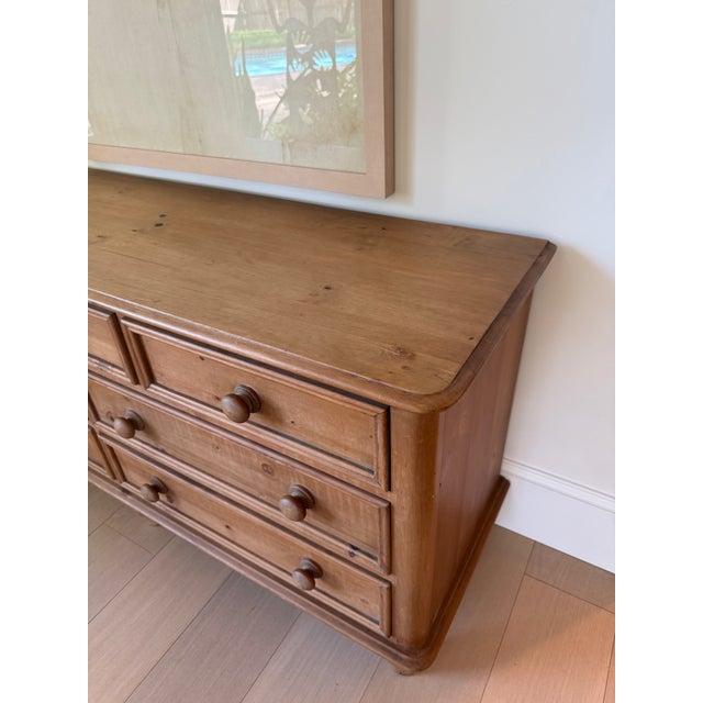 Substantial vintage pine dresser featuring a warm, naturally aged finish, seven paneled drawers, turned wood feet, and...