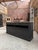 This antique workshop cabinet has been fully restored. It features a raw wood top and a black-patinated cabinet body. It...