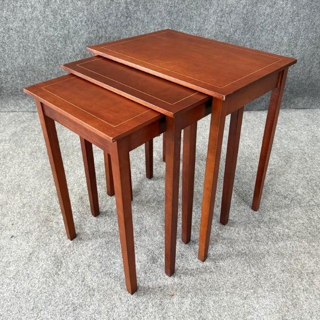 This set of three inlaid mahogany nesting tables features clean, classic lines with delicate inlay detailing that frames...