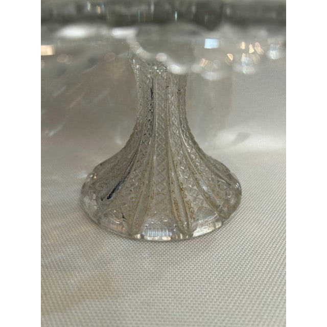 This pedestal cake plate is pressed glass and produced by Duncan Miller between 1894 and 1920. The pattern is “Mardi Gras”...