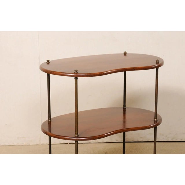 A French three tiered wooden occasional table with brass legs from the mid-20th century. This table from France has three...