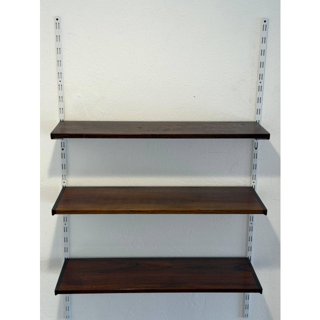 Vintage 1960s Mid-Century Modern wall shelving system in style of Kai Kristiansen, featuring richly grained rosewood...