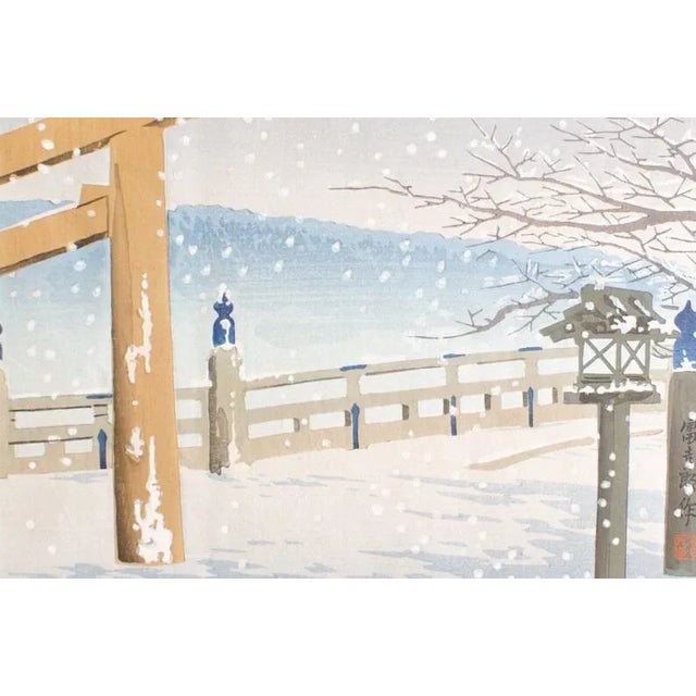 A serene snowy winter's day with bare trees, a pergola, and a hazy view of the mountains in the background this original...