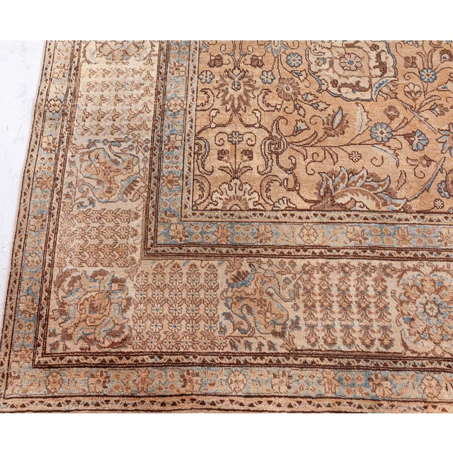 A late 19th century Persian Tabriz carpet, the pale peach field having an allover trellis of playful palmettes, flowering...