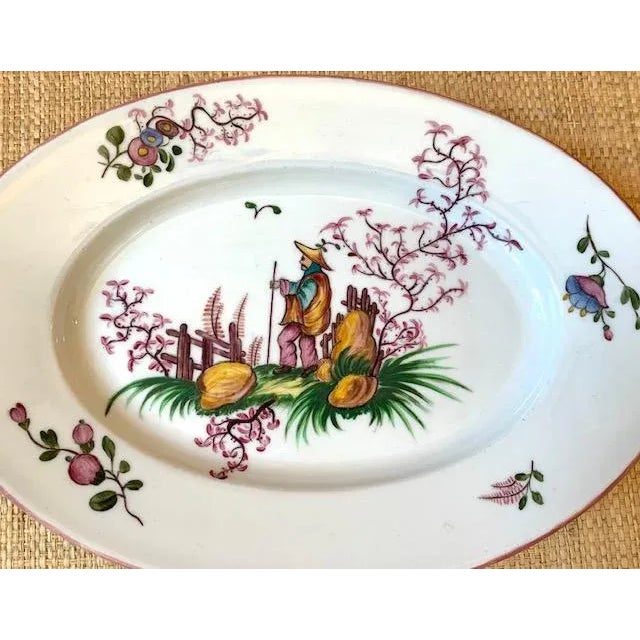 Hand painted in France, this oblong shaped decorative dish features an Asian gentleman in the center, surrounded by flora...