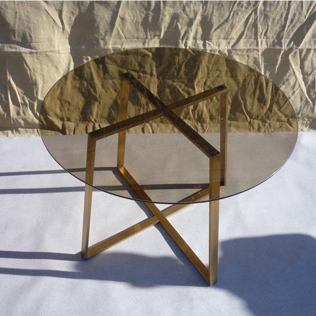 Dining table featuring a smoked glass top on a bronze anodized aluminum frame. A light and elegant piece. The frame is...