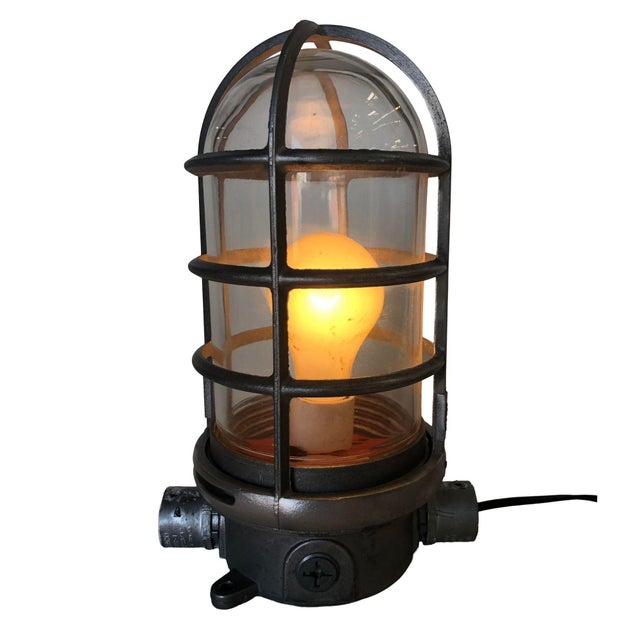 This versatile industrial-style caged iron marine vapor glass light fixture is adaptable as a ceiling mount or wall...
