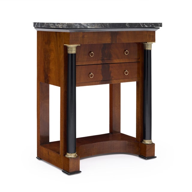 An elegant French Empire side table, circa 1810, combining richly figured mahogany with striking detached ebonized...