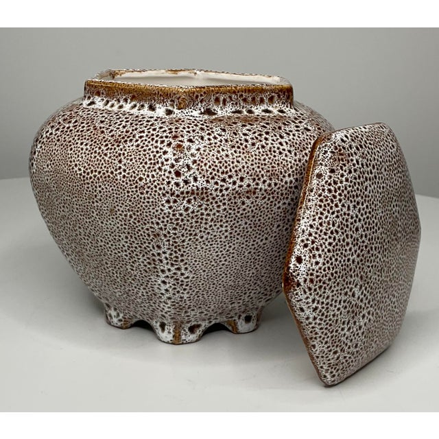 Unique footed jar with lid is hexagon in shape. The brown undercoat with a white glaze creates a unique texture and...