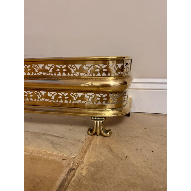 Quality antique Edwardian brass fire fender, having a quality brass fire fender with a pierced brass border above three...