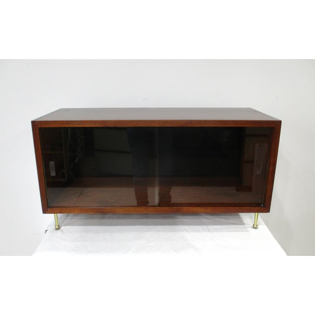 A very unique miniature display cabinet in dark rich walnut with two sliding glass doors on brass legs having rubber feet...