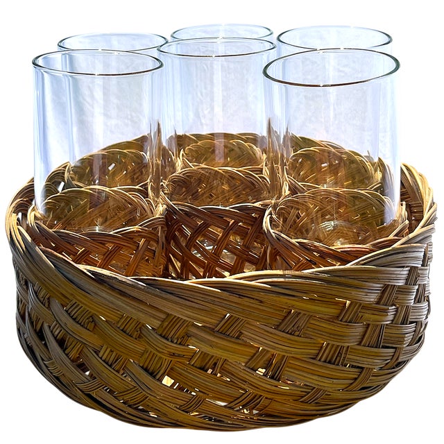 Set of six clear drinking glasses, each nestled in its own 1970s vintage woven rattan sleeve. The set comes complete with...