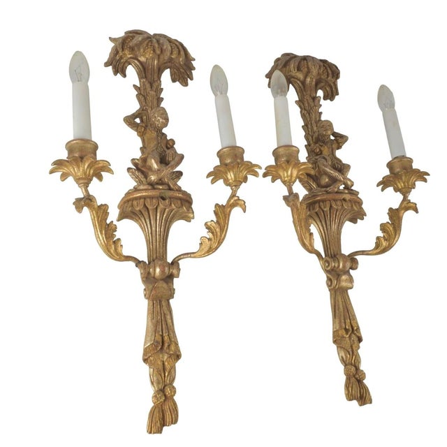 Whimsical Pair of Italian Giltwood Monkey Wall Sconces. Each sconce is carved with exotic monkeys seated beneath palm...
