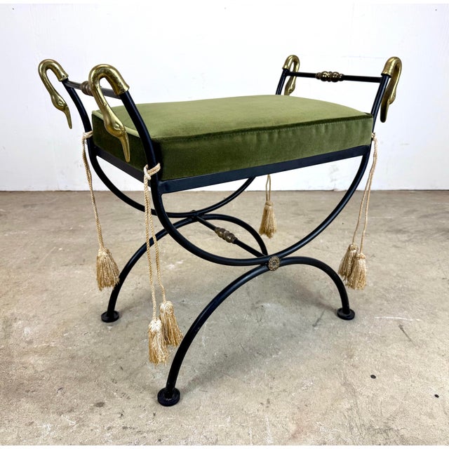 This elegant vintage vanity stool featuring a black iron curule X-frame accented with gleaming brass swan-head finials,...
