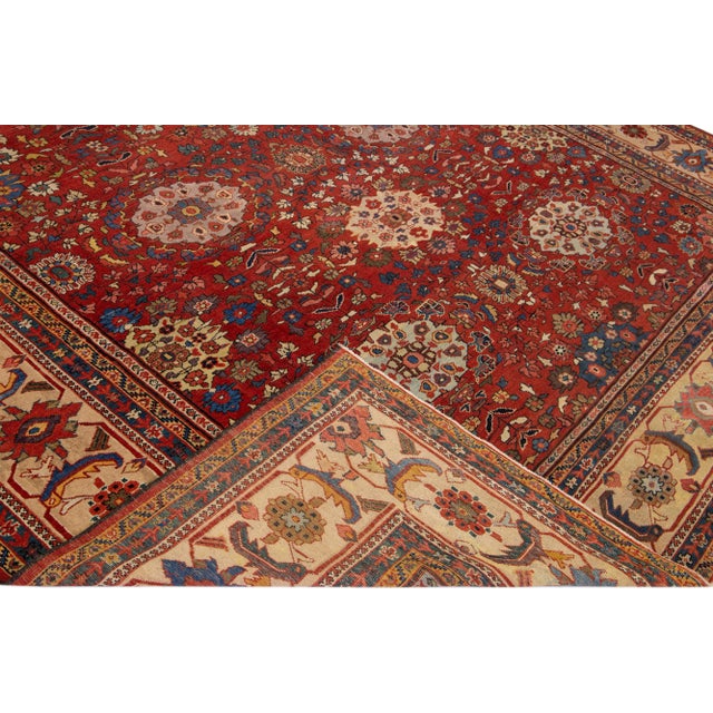 Beautiful Antique Sultanabad hand-knotted wool rug with a red color field. This rug has a beige frame and multicolor...