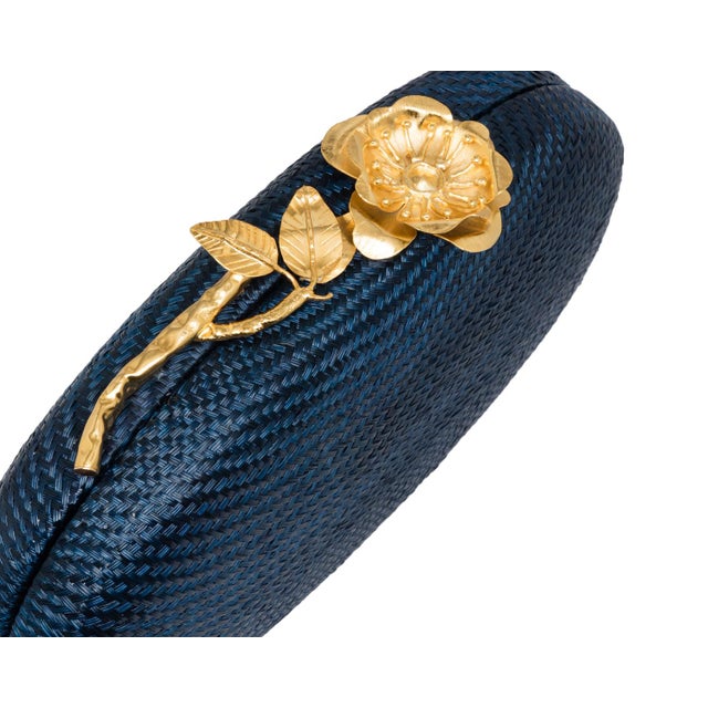 The JOANNA Oval clutch is an ode to enduring elegance, crafted from navy handwoven buntal and crowned with a gold-plated,...