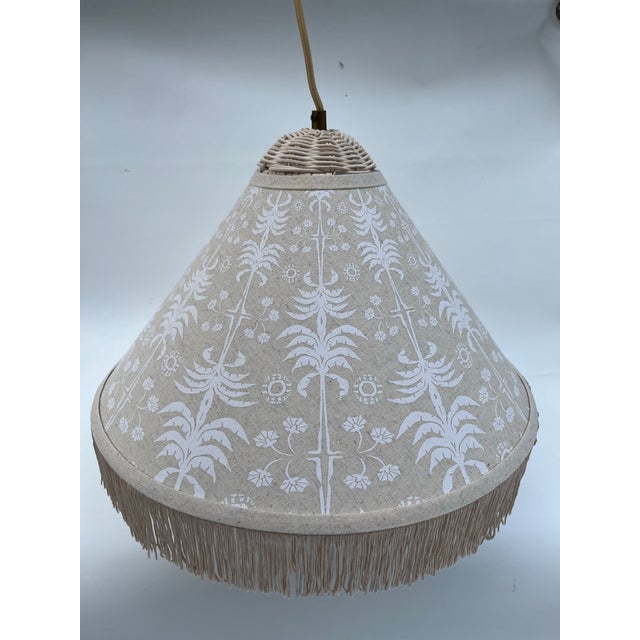 A single round hanging pendant light or lamp featuring a cream colored wicker top, floral printed bright lamp shade, and...