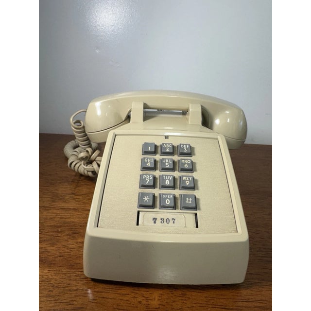 Classic vintage ITT desk telephone in a beige finish featuring a push-button keypad and coiled handset cord. A great retro...