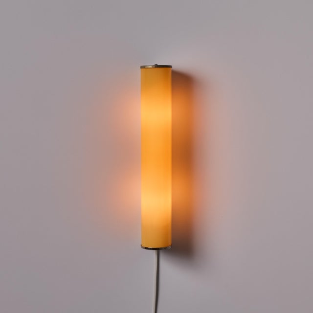 1940s Finnish Yellow Cylindrical Glass and Metal Plug-in Wall Lamp in the Manner of Paavo Tynell A highly refined wall...