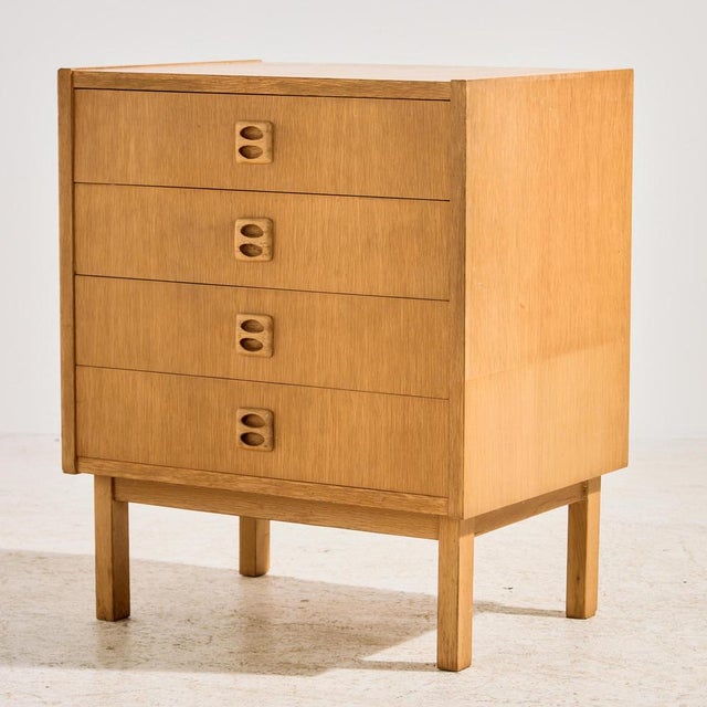 Oak dresser with four drawers and special shaped handles from the 1960s. The surface of the dresser has scratches, stains...