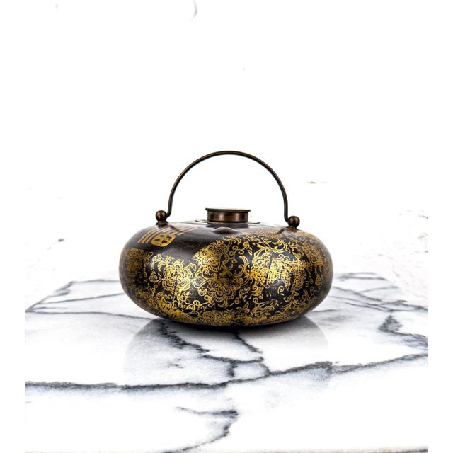 An intricately decorated brass water container, used as a bed warmer, from early 20th century China. The screw-in lid...