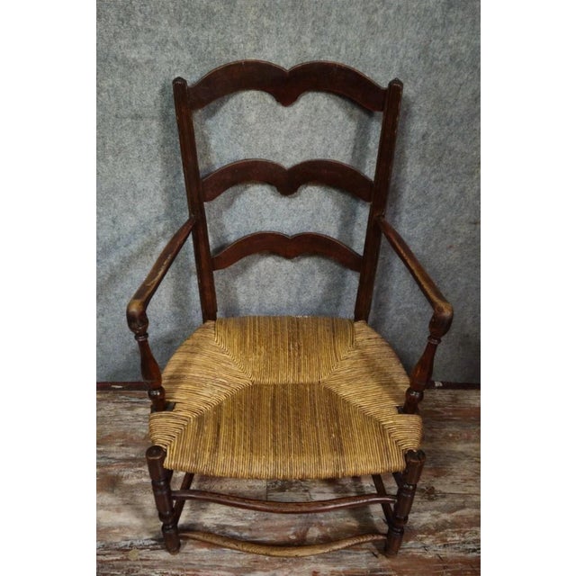 Antique solid wood armchair with a woven straw seat, in a rustic/provincial style. Three-slatted, shaped backrest, turned...