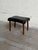 Vintage Danish modern footstool featuring a sculptural black upholstered seat and solid teak legs. The softly curved...