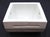 This flush mount toilet paper holder is made of white porcelain over ceramic with a square shape and curved interior back....