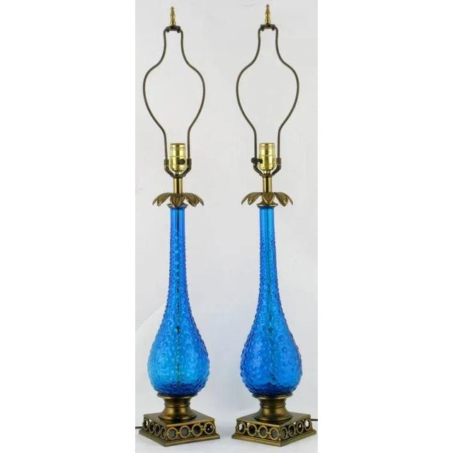 An exquisite pair of blue bubble glass gourd-form table lamps with open brass bases of interlocking rings and floral brass...