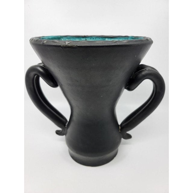 This ear vase by Jean Austruy, made in black ceramic, is distinguished by its superb glaze and its blue-green interior...