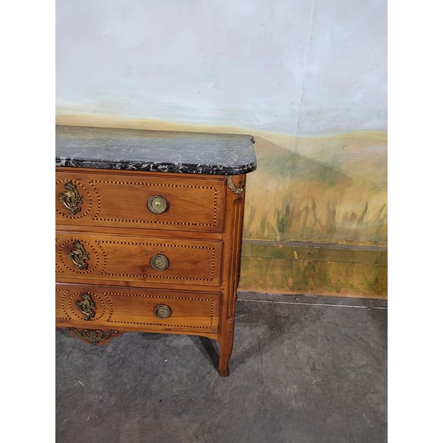 A louis xvi style cherrywood commode with inlaid stringing. an elegant louis xvi style commode with three drawers on the...