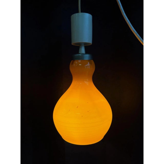 Superb vintage pendant light in orange opaline, typical of 1960s/1970s design. Its curved, teardrop shape gives it an...