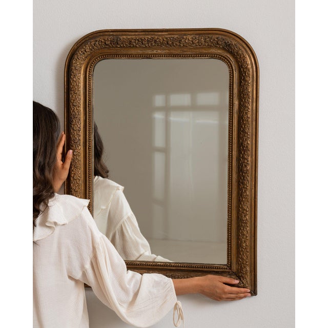 Carved giltwood mirror in Antique Gold. Finished in antique gold, this carved giltwood mirror is distinguished by molded...