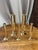 An elegant set of cylindrical, gilded brass candlesticks and bud vases of varying heights, mounted on round bases. These...